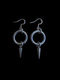 May include: A pair of silver hoop earrings with a pointed spike hanging from each hoop.